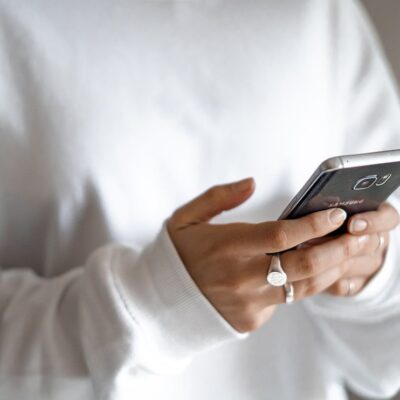 Person using smartphone, wearing white sweater.