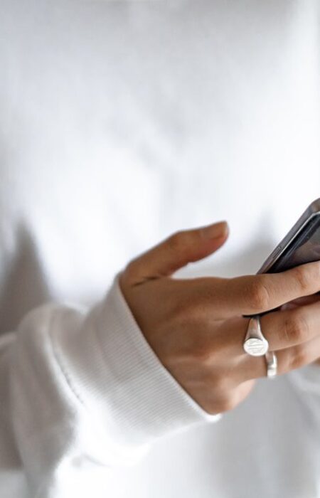 Person using smartphone, wearing white sweater.