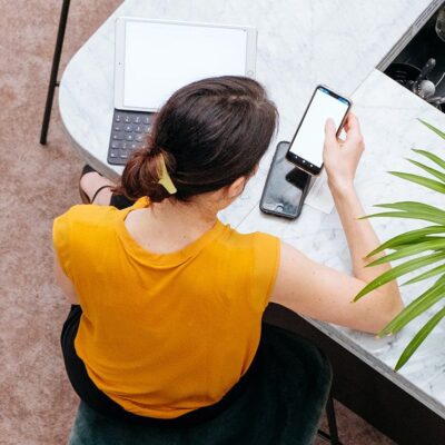 Woman using phone and tablet at cafe.