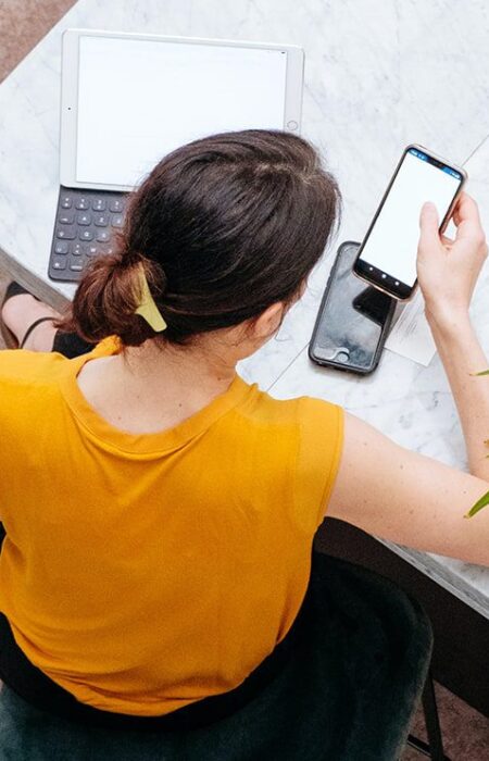 Woman using phone and tablet at cafe.